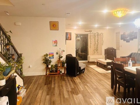 A living room with a wooden floor and a staircase on the left side.