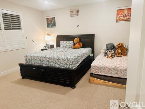 A bedroom with a large bed and a smaller bed with stuffed animals.