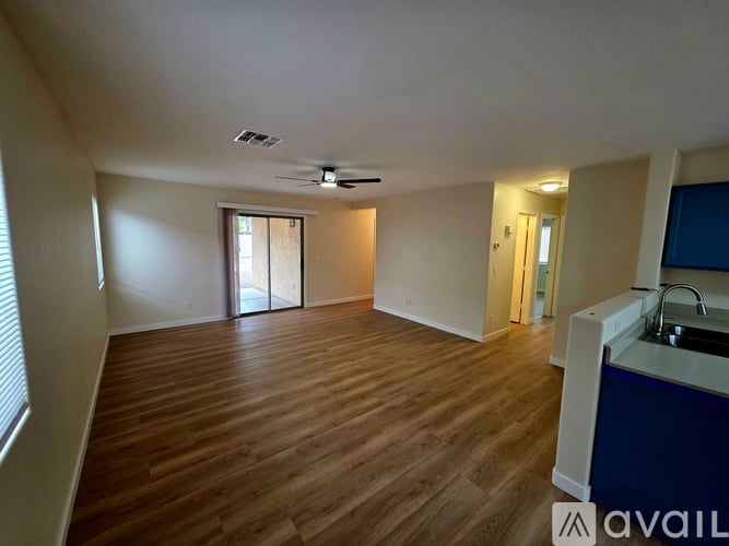 A spacious room with wooden flooring and a ceiling fan.