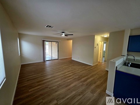 A spacious room with wooden flooring and a ceiling fan.
