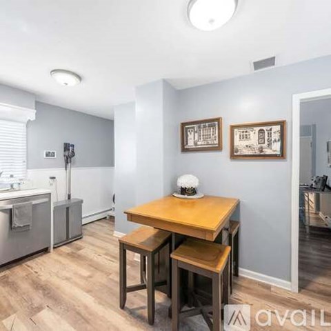 A kitchen with a table and chairs in the foreground and a fridge and cabinets in the background.