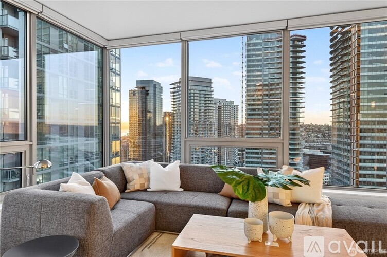 A living room with a grey couch and a wooden coffee table with a plant on it.