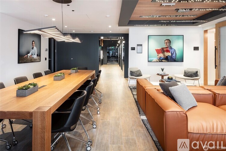 A modern office space with a long wooden table and black chairs.