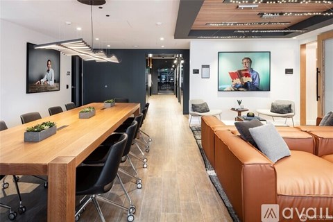 A modern office space with a long wooden table and black chairs.