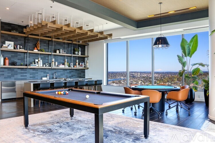 A pool table is in the middle of a room with a view of the city.