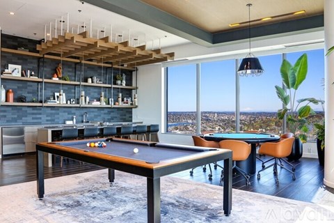 A pool table is in the middle of a room with a view of the city.