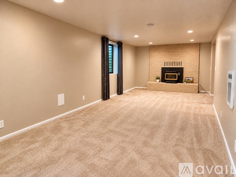 A spacious room with a fireplace and a carpeted floor.