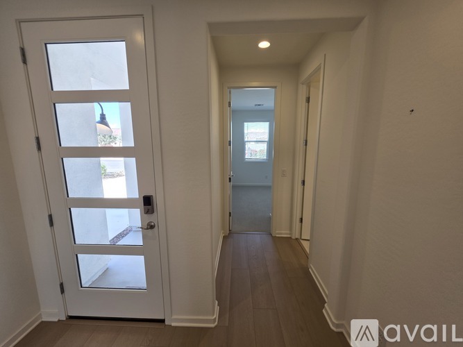A hallway with a white door and a window with a view of a building outside.