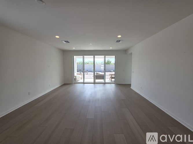 A spacious room with wooden flooring and a large window.