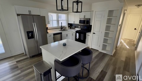 A kitchen with a white table and chairs, a fridge, a microwave, and a sink.