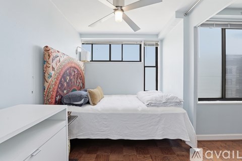 A bedroom with a bed, a ceiling fan, and a window with blinds.