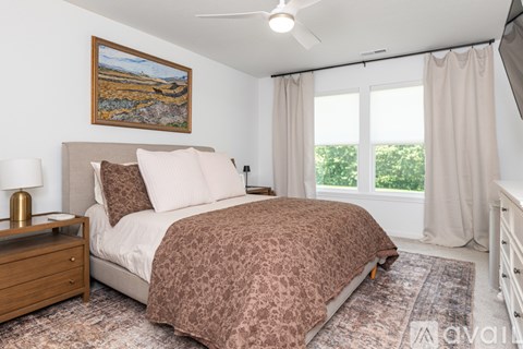 A bedroom with a bed, nightstand, and a painting on the wall.