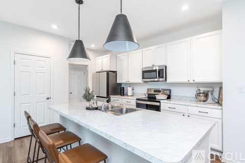 A kitchen with white cabinets and a marble countertop.