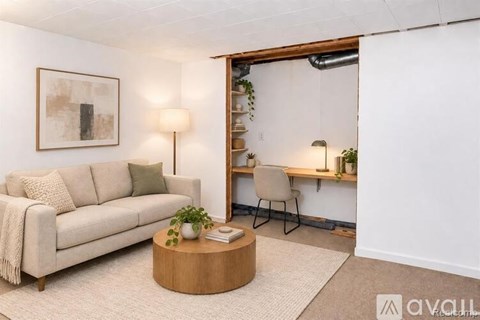 A living room with a white couch, a wooden coffee table, and a painting on the wall.