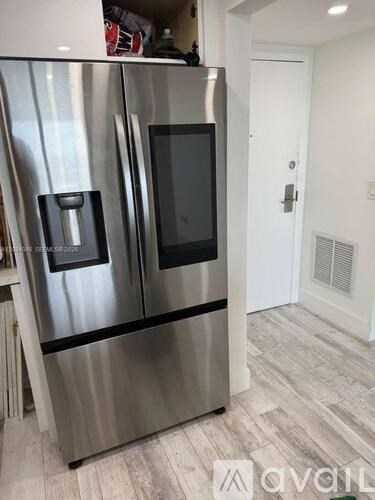 A stainless steel refrigerator with a black handle and a black door is in a kitchen.