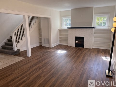 A living room with a fireplace and a staircase.