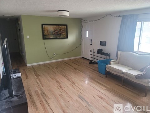 A living room with a white couch and a painting on the wall.