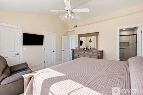 A bedroom with a large bed and a ceiling fan.