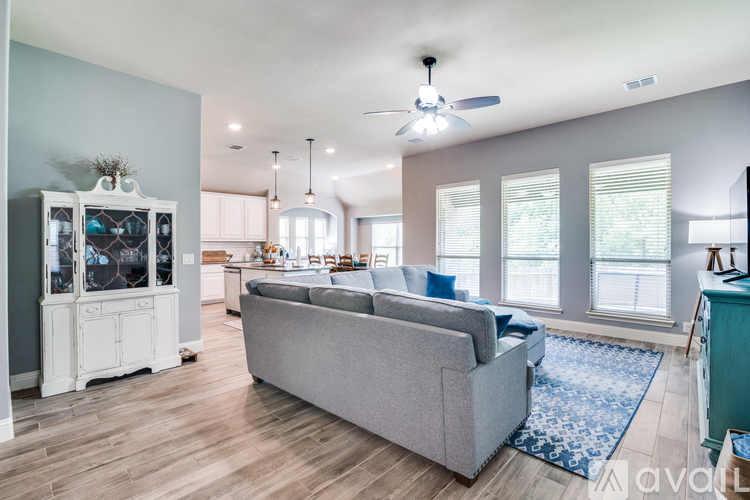 A living room with a grey couch and a ceiling fan.