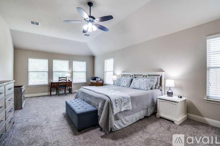 A bedroom with a large bed and a ceiling fan.