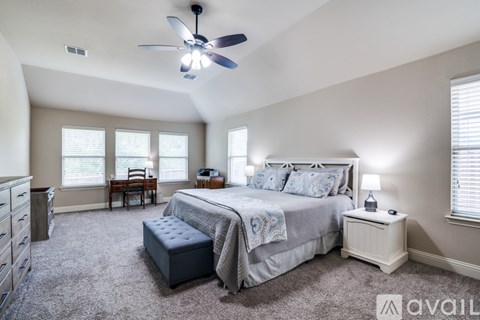A bedroom with a large bed and a ceiling fan.