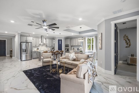 A spacious living room with a marble floor and a ceiling fan.
