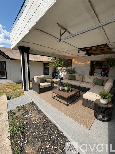 A patio with a white couch, a coffee table, and a rug.