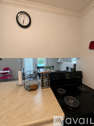 A kitchen with a black stove top and a clock on the wall.