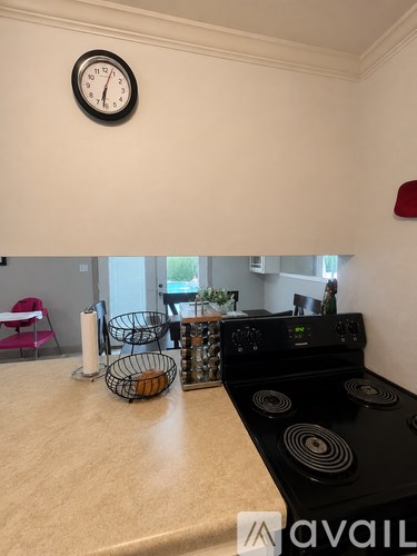 A kitchen with a black stove top and a clock on the wall.