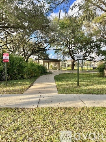 A sidewalk with a sign and trees on the side.