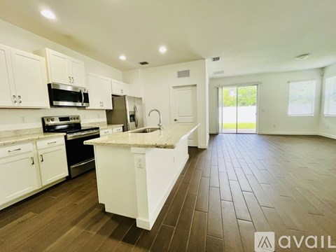 A kitchen with white cabinets and a marble countertop.