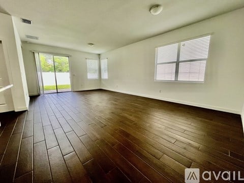 A spacious room with wooden flooring and white walls.