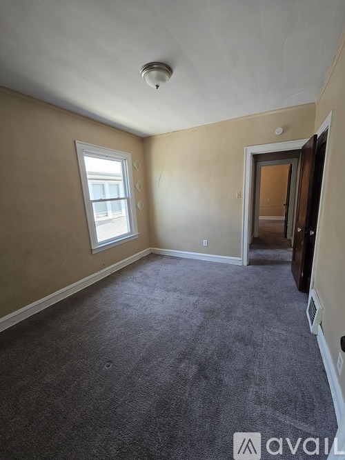 A room with a carpeted floor and a window.