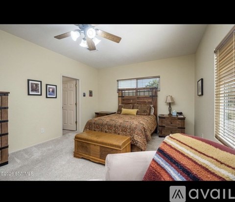A bedroom with a bed, nightstand, and a ceiling fan.