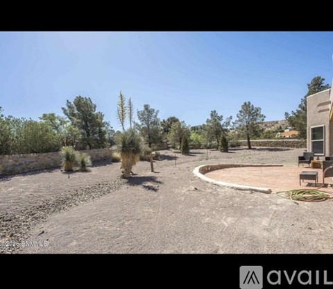 A barren land with a building and trees in the background.