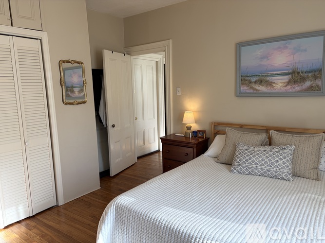 A bedroom with a large bed and a painting on the wall.