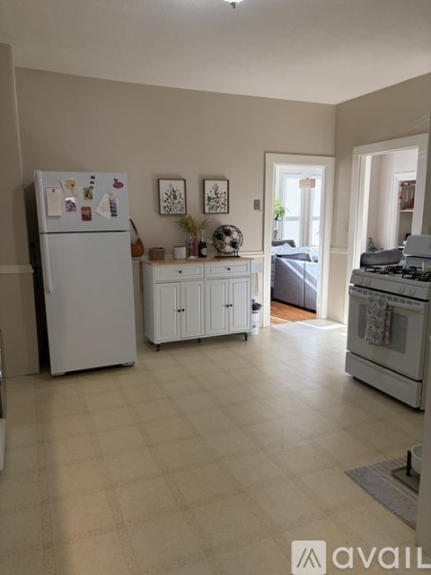 A kitchen with a fridge, oven, and a small table with chairs.