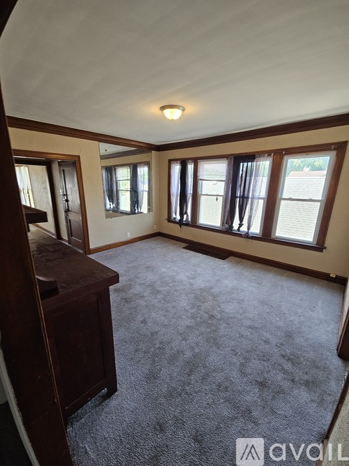 A carpeted room with a desk and a window.