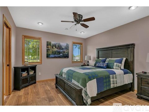 A bedroom with a bed, dresser, and a ceiling fan.