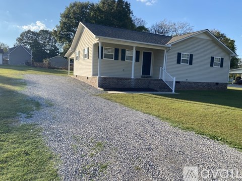 A house with a gravel driveway in front.