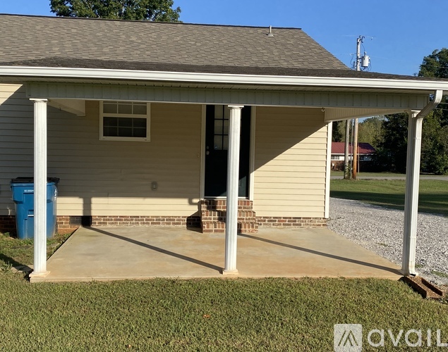 A house with a covered porch and a blue trash can.