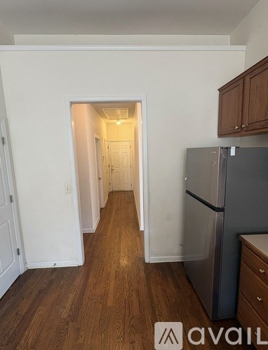 A kitchen with a refrigerator and wooden floors.