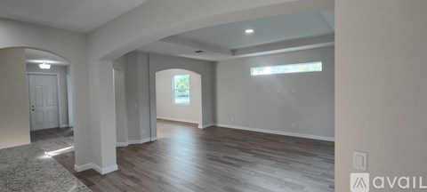 A spacious room with wooden floors and a large archway leading to another room.