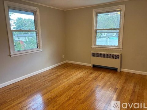 A room with wooden floors and two windows.