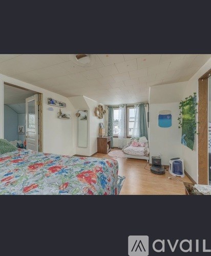 A bedroom with a floral bedspread and a window with curtains.