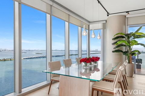 A dining room with a glass table and chairs with a view of the water.