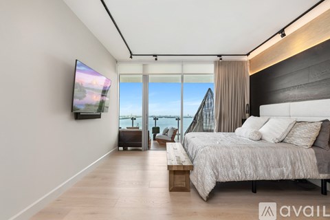 A modern bedroom with a large bed and a flat screen TV mounted on the wall.