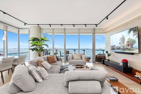 A living room with a large grey sofa and a flat screen TV mounted on the wall.