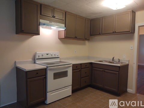 A kitchen with brown cabinets and a white stove.