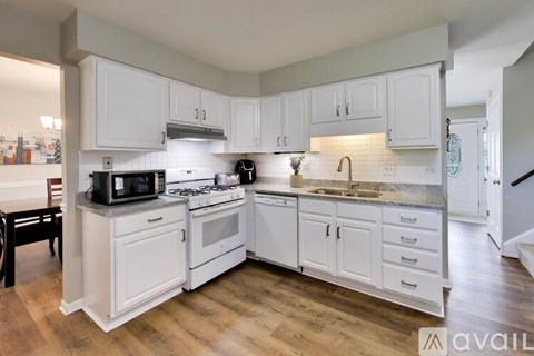 A kitchen with white cabinets and a wooden floor.